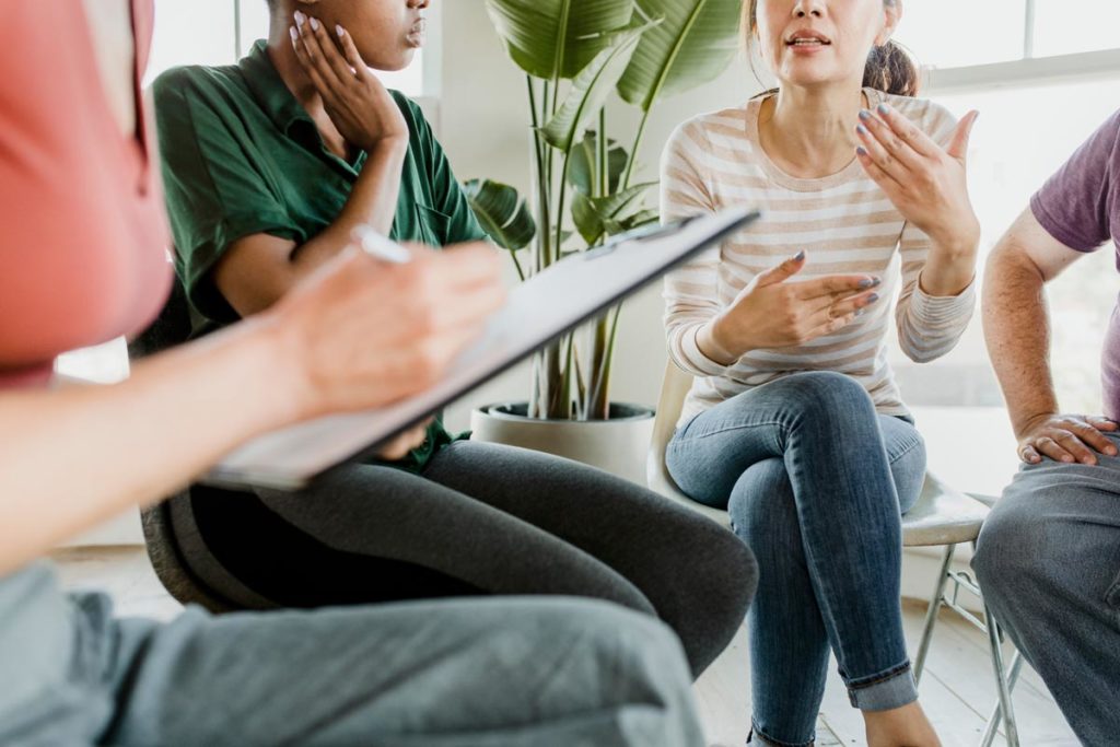 therapist explaining to group of clients the three Cs of addiction