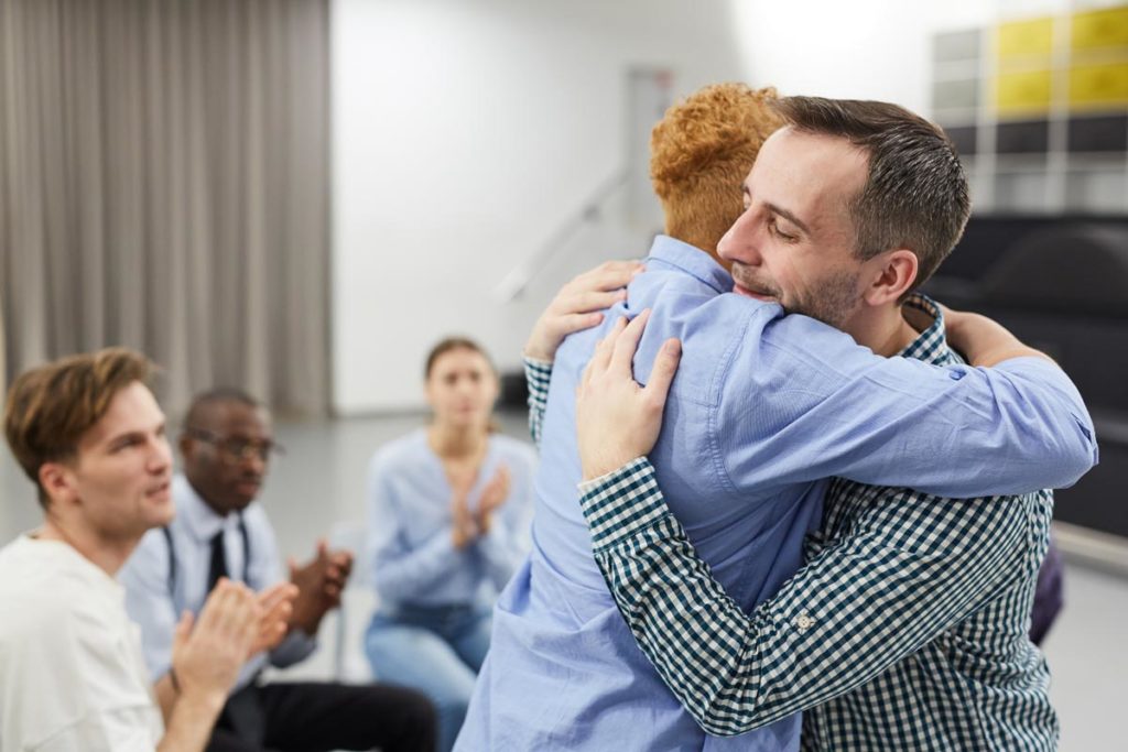 two people hugging in a group therapy environment emphasizing importance of support groups in addiction