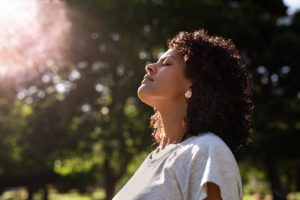 young woman with peaceful contemplative expression standing outside on a sunny day learning what is sober spring as she completes the organization's 90-day challenge