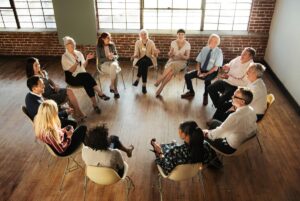 group of men and women in therapy session discussing if you can work while in rehab