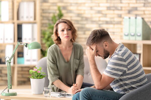 young man talking to female therapist about anger issues and seeking anger management treatment