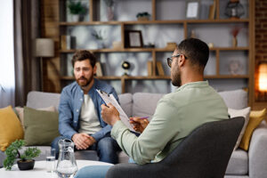 young man discussing depression treatment with his therapist in an office setting.