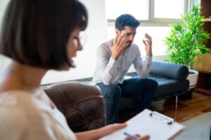 female therapist explains to distraught man why he needs a drug rehab program