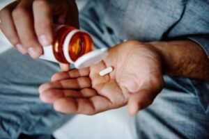 man dumping his last prescription painkiller into his hand and resolving to seek a painkiller rehab program