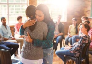 two women embracing after a group therapy session as part of a benzo abuse rehab program