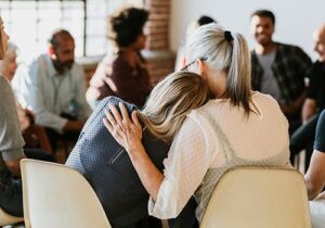 two members of a group therapy sessions hug in support of one another as part of a cocaine rehab program