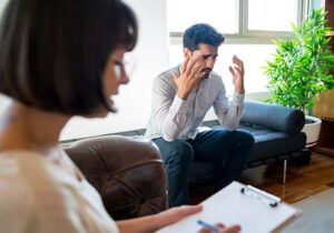 distraught young man in office setting talking to therapist about entering a depression treatment program