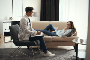 male therapist talking one-on-one with female client on a couch in a professional setting as part of an individual therapy program