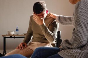 distraught young man being consoled during a trauma therapy program session