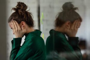 Young, distraught woman leaning against mirrored window wondering how long does MDMA stay in your system