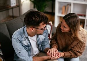 couple sitting together on couch as young woman earnestly encourages young man to seek a relapse prevention therapy program