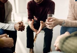 group of men and women seated in a circle as part of a substance abuse treatment program led by an addiction specialist