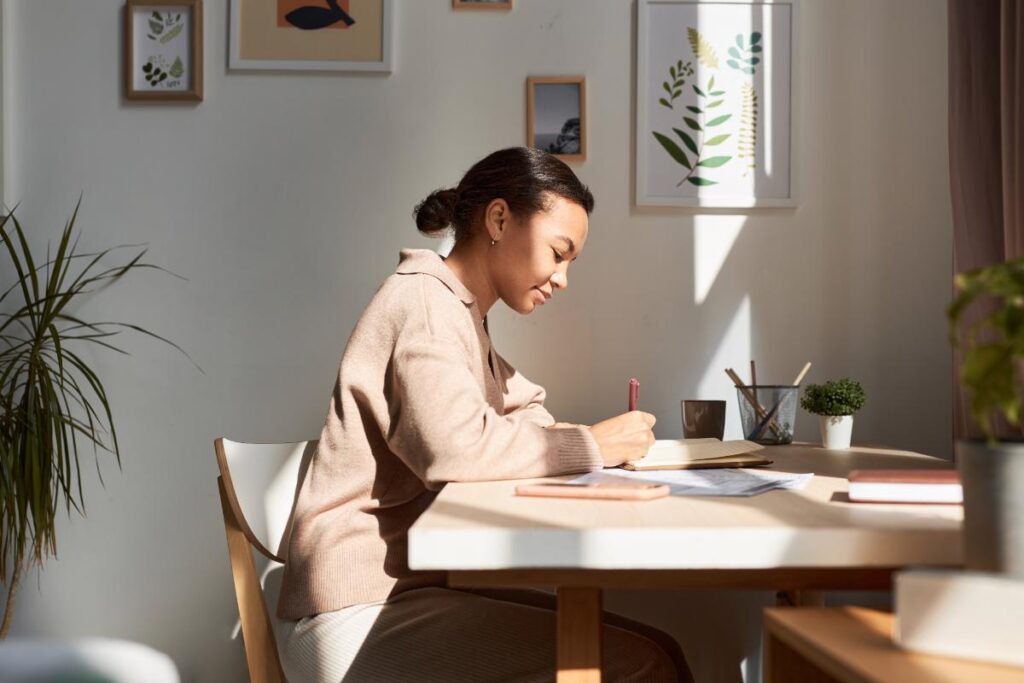 young woman seated at desk with pen and paper setting sober goals for the new year
