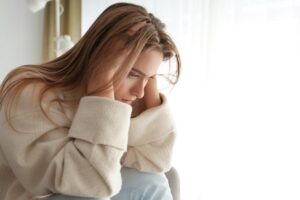 young, distraught woman clutching her head as she struggles with stress and anxiety