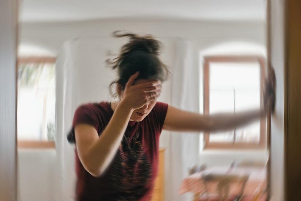 woman leaning against her living room wall with her head in her hand experiencing common hydrocodone side effects