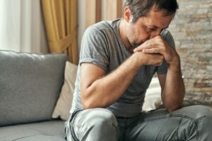 middle aged man seated on couch deep in thought and pondering how does anxiety affect my relationships?